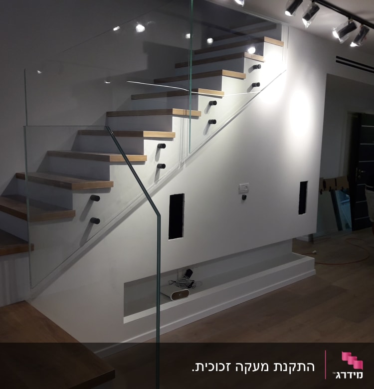 מעקה זכוכית שקוף לאורך גרם מדרגות עץ